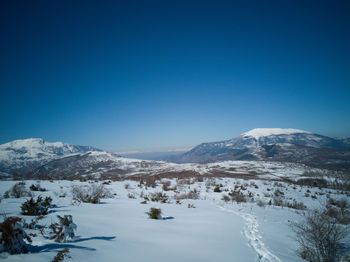 Scenic view of snowcapped mountains against clear blue sky