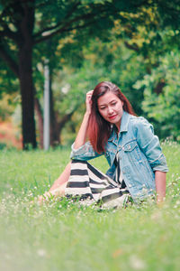 Portrait of beautiful young woman sitting on land