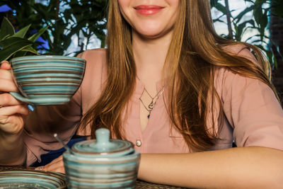 Midsection of woman holding coffee cup at cafe