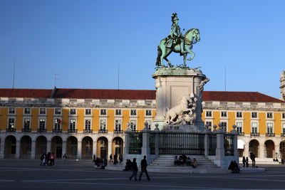People by statue of king jose i at praca do comercio against sky