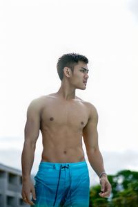 Young man looking away against sky