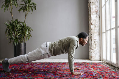 Smiling man practicing planks on carpet at home