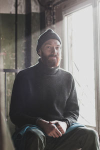 Portrait of young man sitting by window