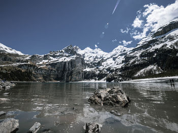 Scenic view of lake by snowcapped mountain against sky