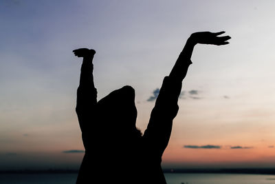 Close-up of silhouette hand against sky during sunset