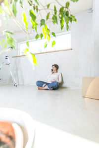 Young woman using phone while sitting on wall
