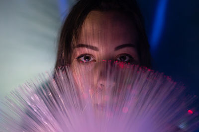 Close-up portrait of young woman holding fiber optic