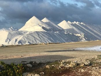 Heaps of salt on land against sky