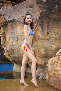 Portrait of young woman standing against rock