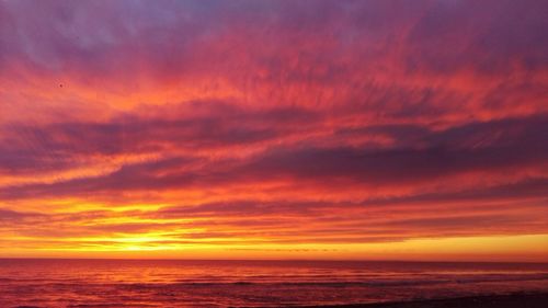 Scenic view of sea against dramatic sky during sunset