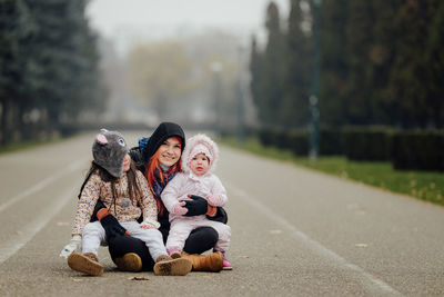 Rear view of friends sitting on road