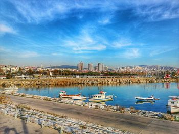 Sailboats moored in harbor against sky in city