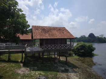 House by lake against sky