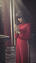 Young woman praying while holding incense stick in temple