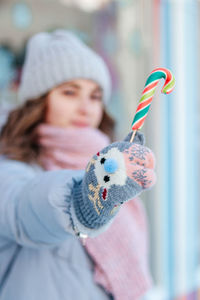 Close-up portrait of woman holding a candy cane 