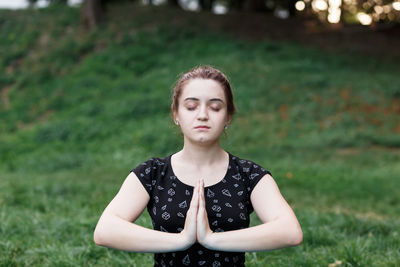 The relaxed girl is doing yoga in the park on carpet