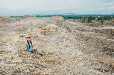 High angle view of young woman sitting on rocky mountain