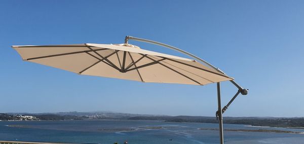 Lifeguard hut on sea against clear blue sky