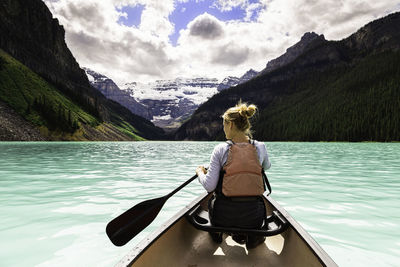 Rear view of woman rowing boat on lake