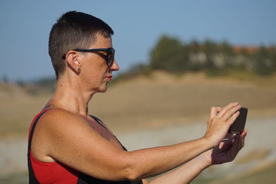 Close-up of young man using mobile phone at beach