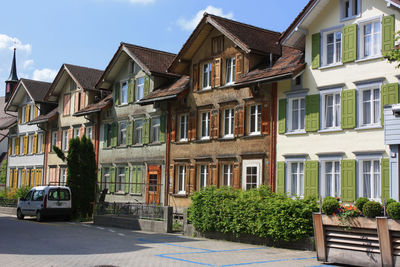 Residential buildings by street against sky