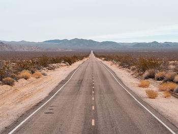 Road leading towards mountains against sky