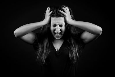 Portrait of young woman against black background