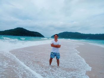 Young man standing on beach against sky