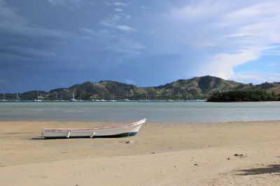 Deck chairs on beach against sky