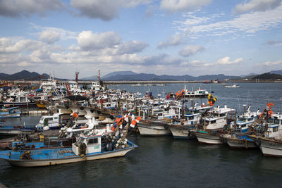 Boats moored at harbor against sky