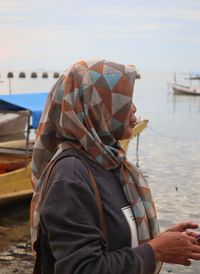 Woman holding boat in sea against sky