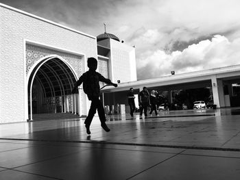 People walking on building against sky in city