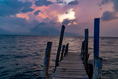 Wooden pier on sea against sky during sunset