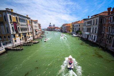 Boats in canal amidst buildings in city