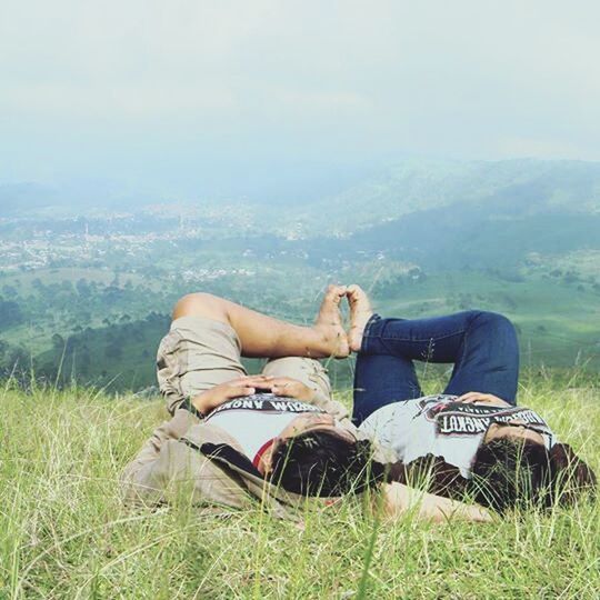 lifestyles, relaxation, sitting, leisure activity, grass, lying down, resting, young adult, field, casual clothing, relaxing, low section, young women, sky, person, legs crossed at ankle, landscape