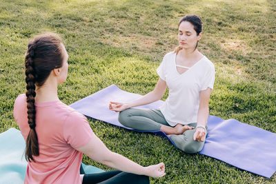 Two young women in the park doing yoga. exercising outdoors, healthy lifestyle