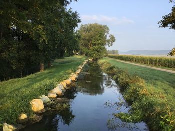 Scenic view of canal amidst trees against sky