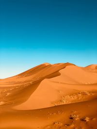 Scenic view of desert against clear blue sky