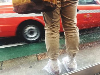 Low section of man standing by bus