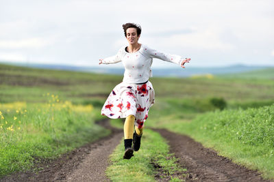 Joyful young woman in skirt running in canola field in the spring