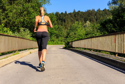 Full length rear view of woman walking on road
