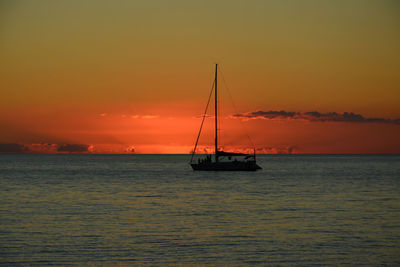 Silhouette sailboat in sea against romantic sky at sunset