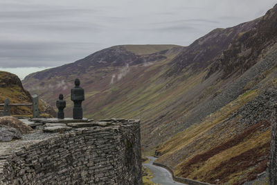 Rear view of sculpture looking at mountain range against sky