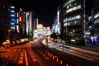 Light trails on city street amidst buildings at night