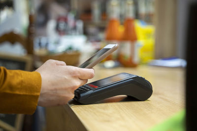 Woman using smart phone for contactless payment at grocery store checkout