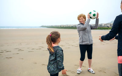 Happy family playing with ball at beach