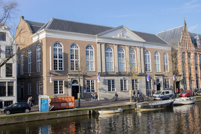 Boats moored in canal by buildings against sky in city