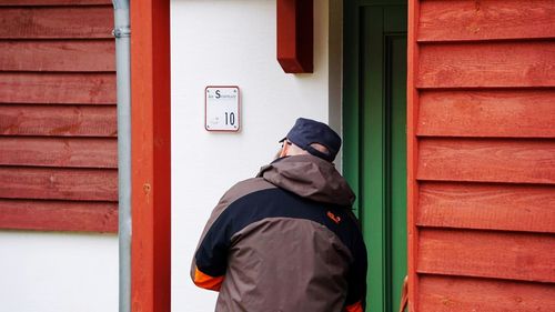 Man standing against red door