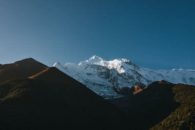 Scenic view of snowcapped mountains against clear blue sky