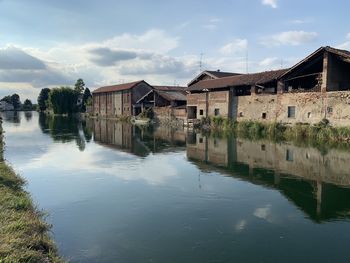 Houses by lake and buildings against sky